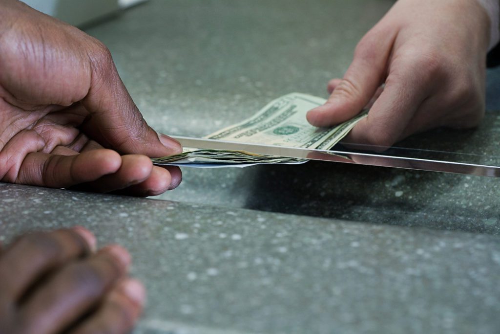 Bank teller hands money to a customer.